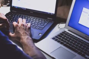 A data analyst with two laptops, typing on one next to the other, for data visualization